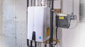 A tankless water heater on a cement wall in a basement.