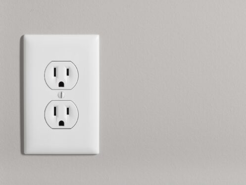 A white home electrical outlet on a light grey wall.